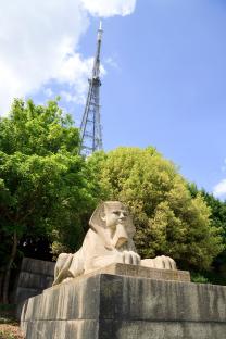 Stone sphinx with a television transmitter tower in the background.