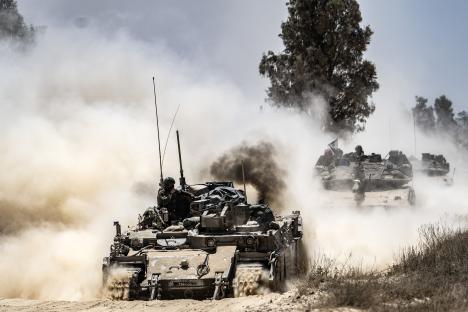 Israeli army tanks and military vehicles moving through dust.