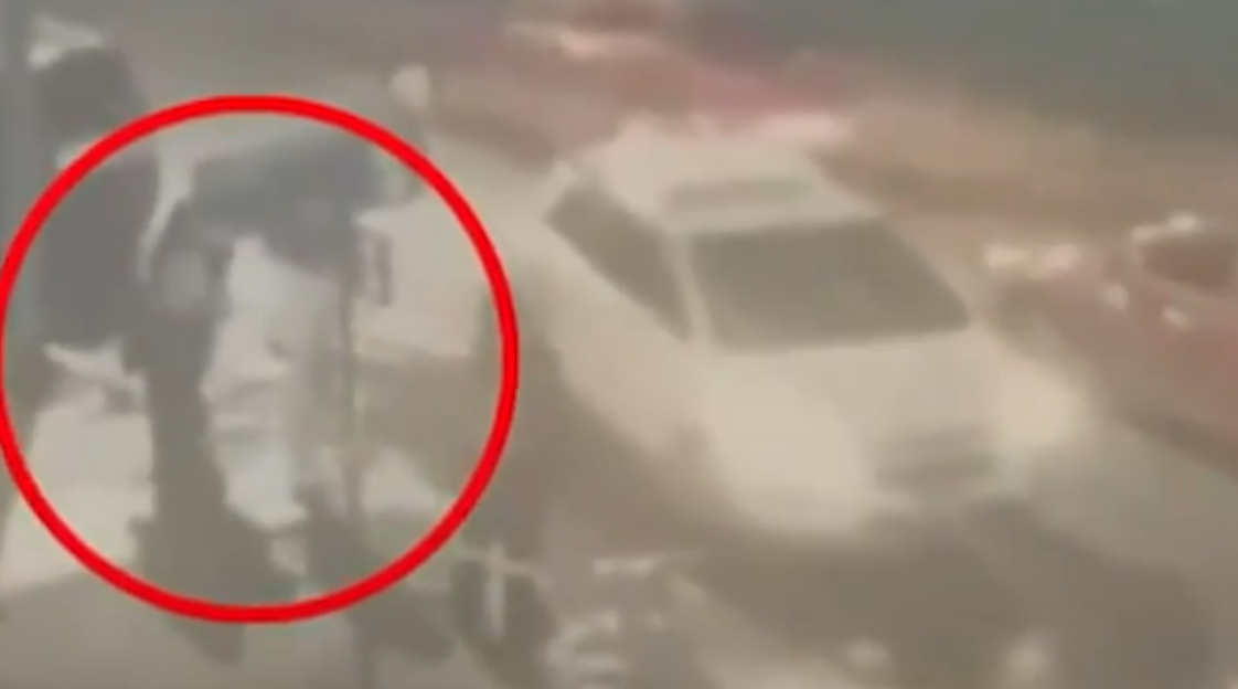 Two people standing next to a car, circled in red.