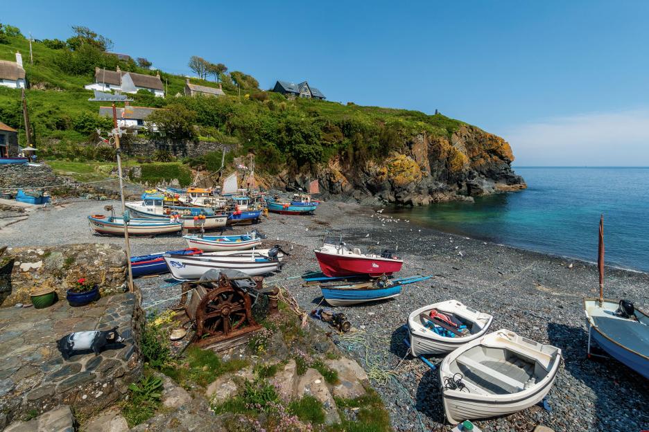 Fishing boats resting on the rocky shore of Cadgwith Cove, Cornwall, England.