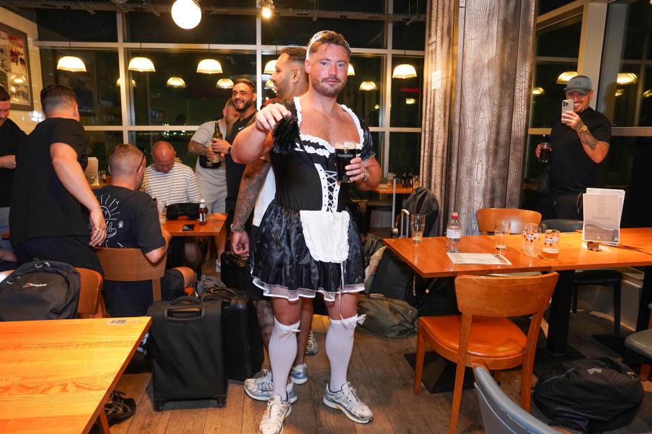 Man in maid costume holding a Guinness in a pub.