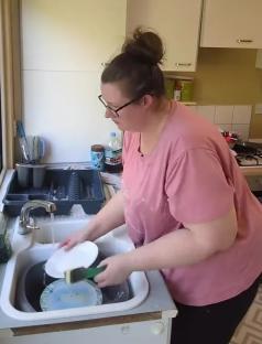 Woman washing dishes in a kitchen sink.