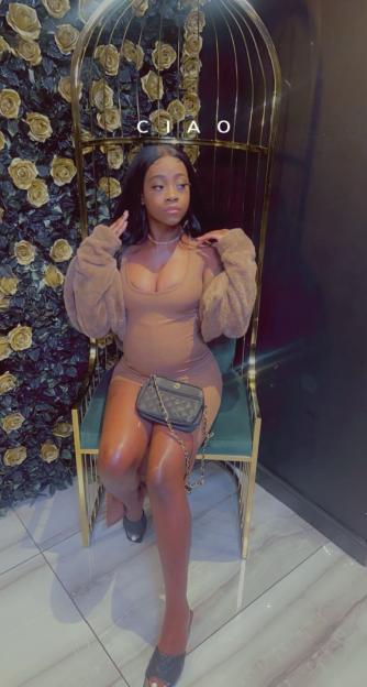 Woman in brown dress sitting on a gold chair.