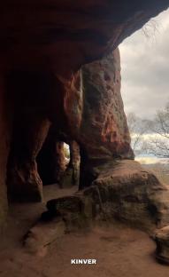 Interior of Kinver Cave, UK, showing sandstone rock formations and cave entrances.