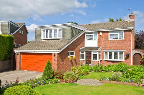 1980s-style five-bedroom house with an orange garage door and well-maintained garden.