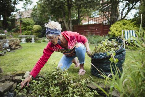 Senior woman weeding her garden pond.