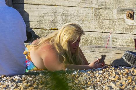 Gemma Collins at the beach looking at her phone.