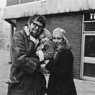 a black and white photo of a man and woman holding a little girl