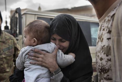 A crying woman holds a baby close.