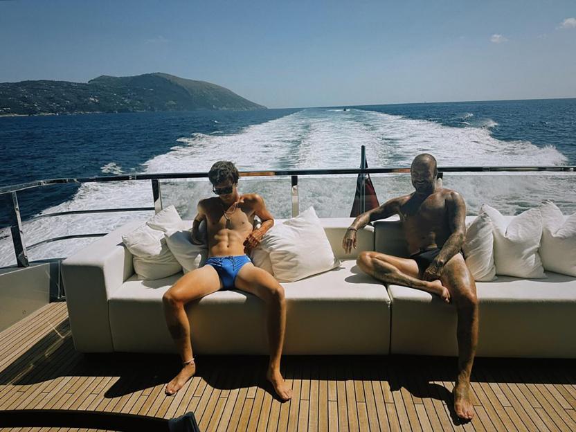 Two men in swimsuits relaxing on a yacht.