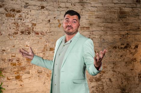 Luke Worley in a light green suit, gesturing with his hands.