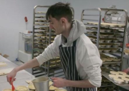 A baker preparing pies in a commercial kitchen.