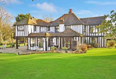 Large black and white Tudor-style house with a sunroom.