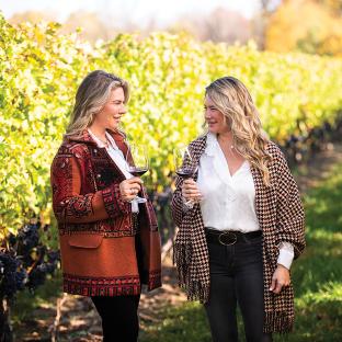Two sisters enjoying wine in a vineyard.