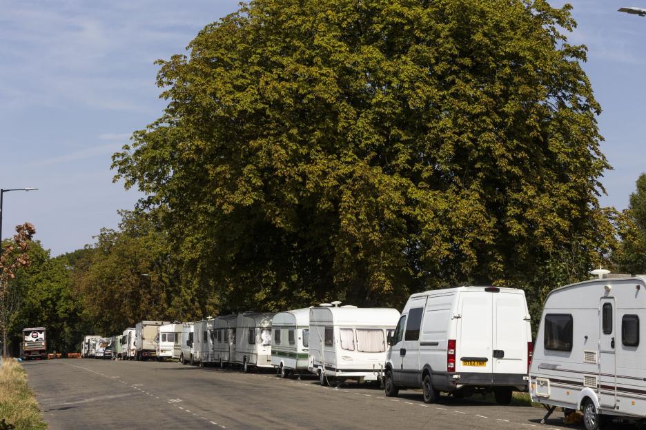 Row of vans and caravans parked along a road.