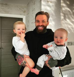 Aaron Chalmer holding his two young children.