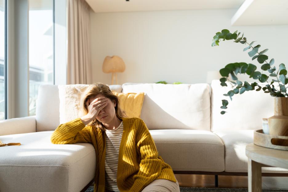 Woman suffering from a headache, covering her eyes with one hand.