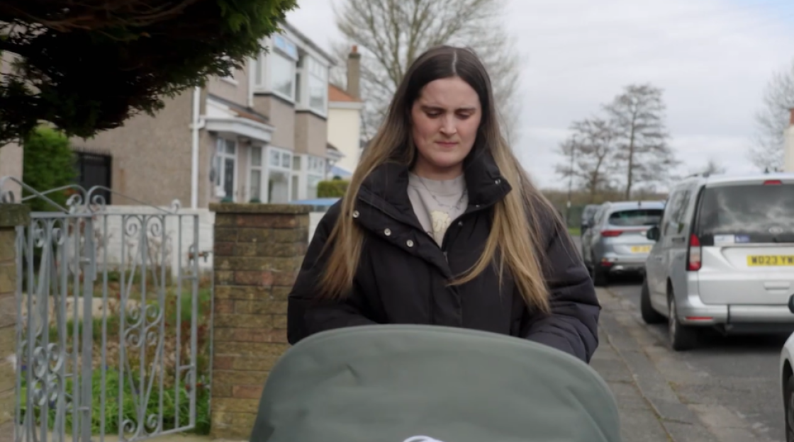 Woman pushing a stroller down a residential street.