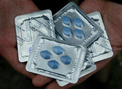 Hand holding Kamagra tablets.