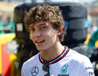 a young man wearing a petronas shirt smiles for the camera