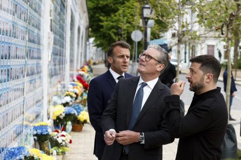 Zelenskyy, Macron, and Starmer visiting a memorial wall for fallen Ukrainian soldiers.