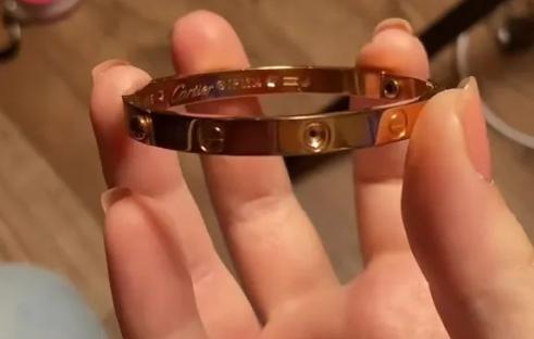 Hand holding a Cartier Love bracelet.