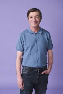 Portrait of John, a man wearing a blue shirt and jeans.