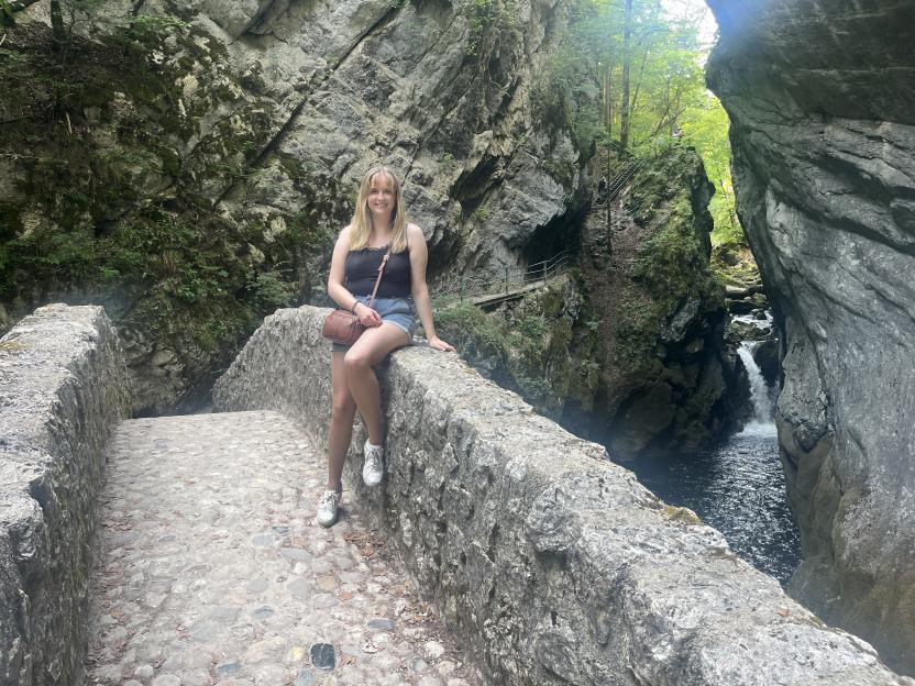 Woman sitting on a stone bridge overlooking a rocky gorge.