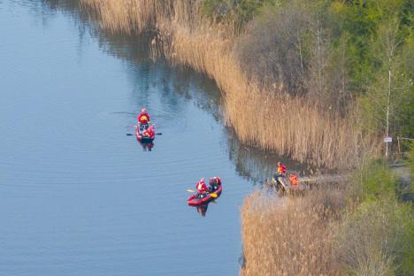 Aerial view of emergency responders in small boats searching a lake.