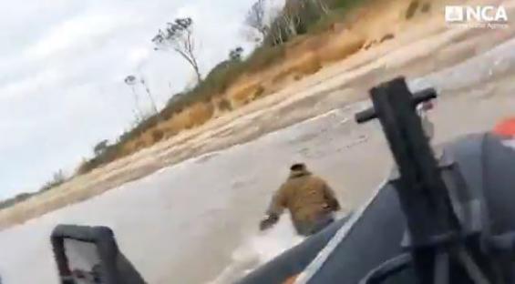 A man swimming away from a boat near a beach.