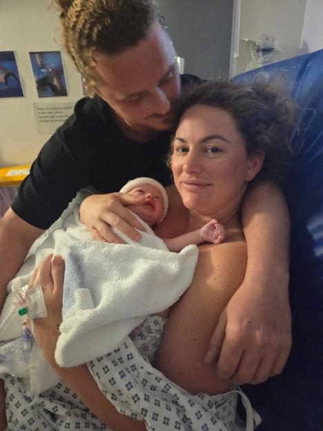 Parents holding their newborn baby in a hospital.