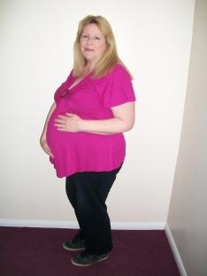 Pregnant woman in pink shirt and black pants.