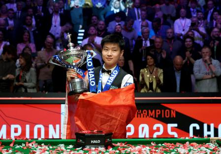 Zhao Xintong celebrates winning a snooker championship trophy.