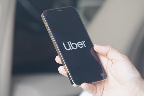 Photo illustration of a woman using the Uber app on her smartphone.