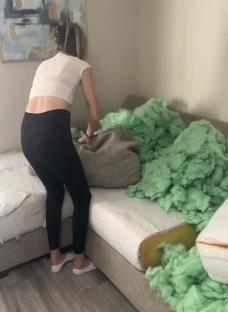 Woman removing stuffing from sofa cushions.