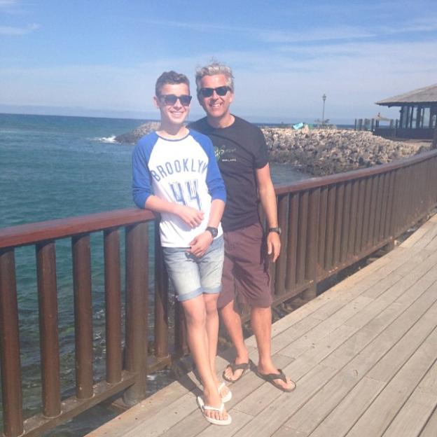 George Clarke and his dad Sean Clarke on a boardwalk by the ocean.