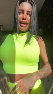 Woman in neon green top and matching bottoms speaks to camera.