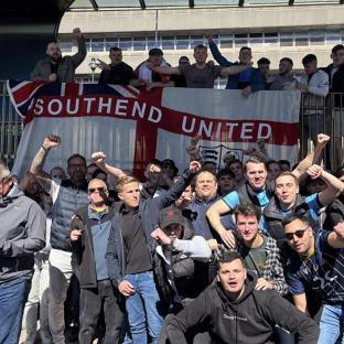 Large group of Southend United fans posing with a team flag.