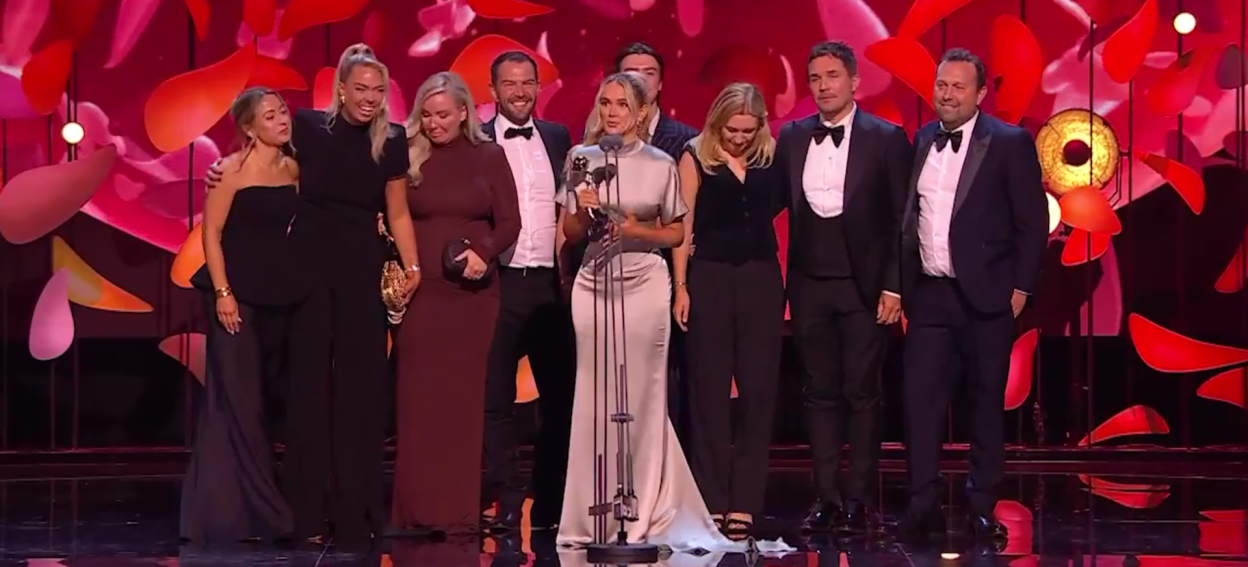 Group of people accepting an award on stage.
