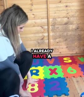 Woman placing alphabet and number foam floor mats inside a wooden shed.