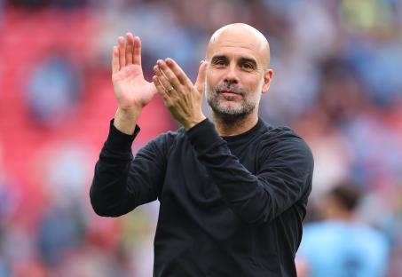 Pep Guardiola applauding at a soccer game.