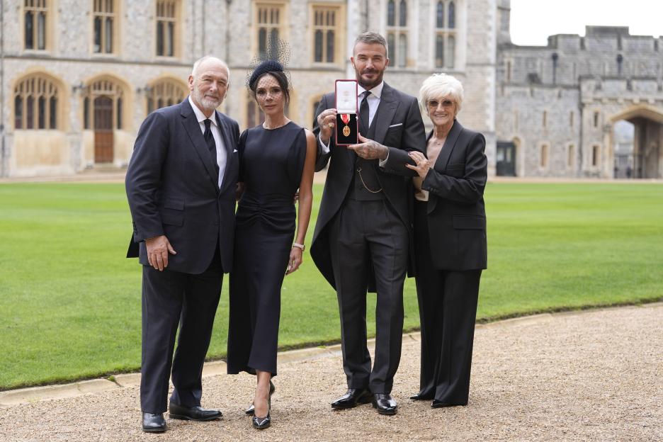 David Beckham holds his OBE medal, accompanied by his family, outside Windsor Castle.