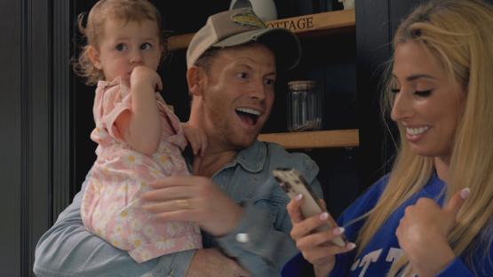 Stacey Solomon, Joe Swash, and their daughter looking at a phone.