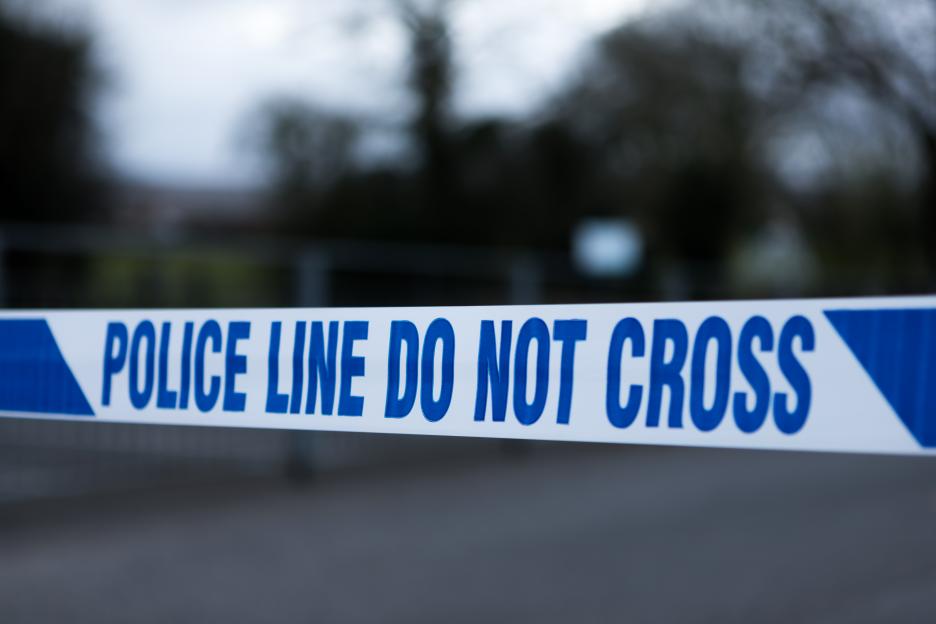 White and blue police tape reading "POLICE LINE DO NOT CROSS" across a blurred background.