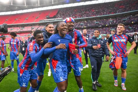 Crystal Palace players celebrating a victory, one holding a Player of the Match trophy.