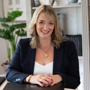 Portrait of a smiling woman sitting at a desk.