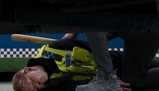 Injured police officer lying on the ground near a bloody baseball bat.