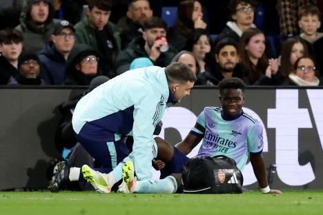 Bukayo Saka of Arsenal receiving medical attention on the field.