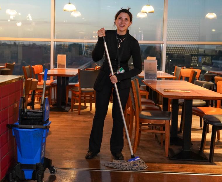 A woman mopping the floor of a restaurant.