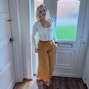 Woman in white top and mustard pants.